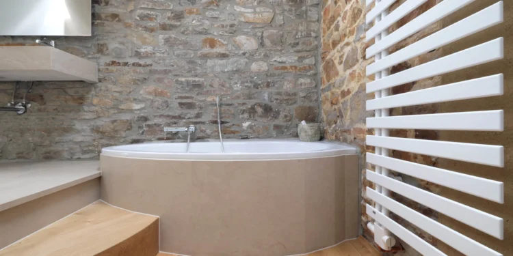 Badezimmer mit rustikaler Steinwand Badewanne mit Natursteinverkleidung