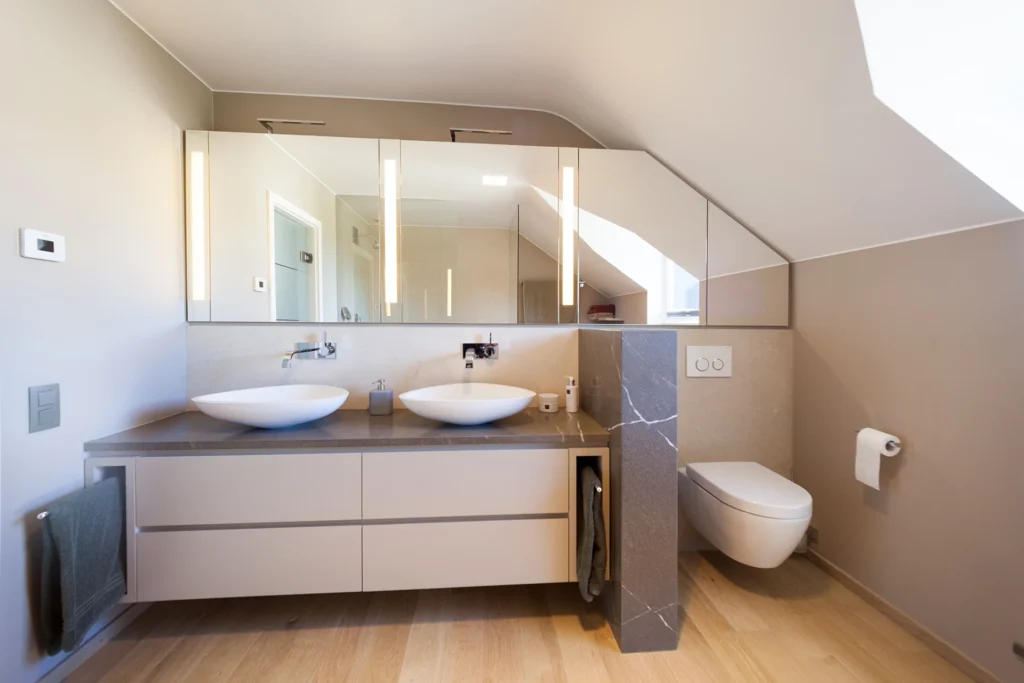 Badezimmer mit Doppelwaschtisch und WC-Bereich in Naturstein verkleidet