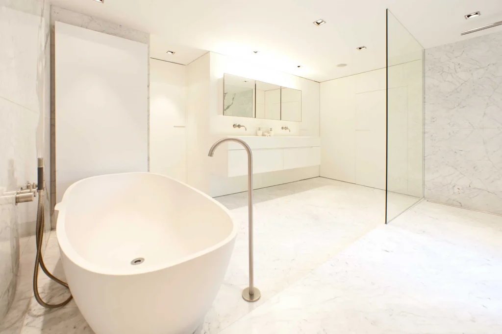 Badezimmer mit weißem Marmor und Vola Armaturen